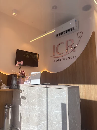 Recepção da ICR Odontologia com bancada em mármore claro e letreiro da clínica