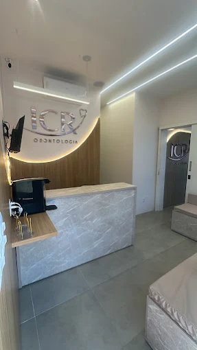 Vista da recepção da ICR Odontologia com painel de madeira clara e iluminação indireta